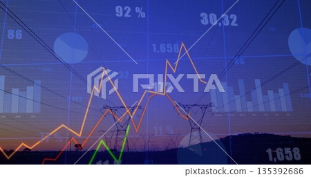 Displaying transmission towers and power lines rising on hill at dusk, with financial data overlays 135392686