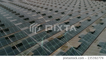 Spanning photovoltaic panels stretching across solar farm grid, with metal rails and supports 135392774