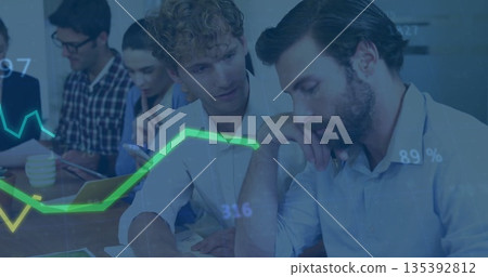 Two male analysts in blazers reviewing reports in conference room, examining paper charts 135392812