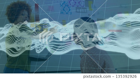 Collaborating women wearing casual tops holding laptop pointing at whiteboard in office, with wave Collaborating women wearing casual tops holding laptop pointing at whiteboard in office, with wave 135392926