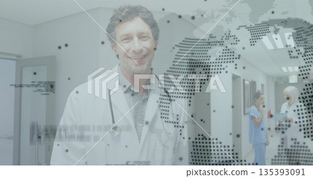 Smiling doctor holding clipboard and wearing stethoscope in hospital corridor near signage 135393091