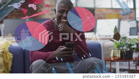 Smiling man scrolling smartphone in lounge with sofa, yellow pillow, brass planter, data overlays 135393387