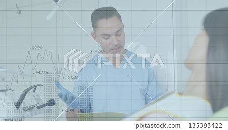 Consulting dentist in blue scrubs reviewing chart with patient in treatment room 135393422