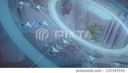 Typing agents wearing headsets at open-plan office desk with keyboards, plant and network overlay Typing agents wearing headsets at open-plan office desk with keyboards, plant and network overlay 135393542