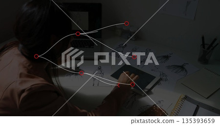 Leaning designer focusing on tablet at desk in design studio, with sketches, notebook and laptop 135393659