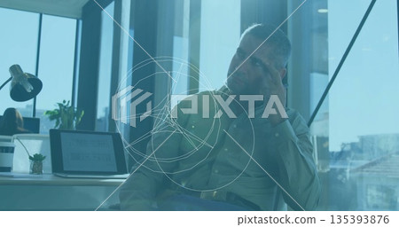 Sitting worker in shirt studying data at lamp-lit office desk, with succulent and overlay graphics Sitting worker in shirt studying data at lamp-lit office desk, with succulent and overlay graphics 135393876