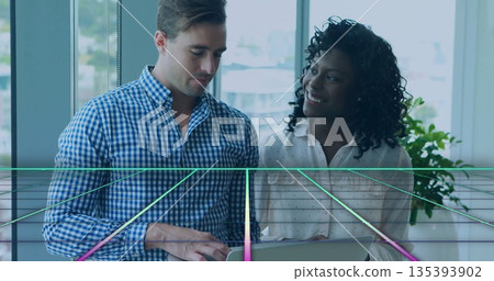 Colleagues wearing business attire working on laptop at desk beside window overlooking city skyline 135393902