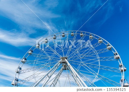 Ferris wheel under blue sky, capturing fun and adventure on a sunny day. Ferris wheel at the amusement park adjacent to the hotel Ferris wheel under blue sky, capturing fun and adventure on a sunny day. Ferris wheel at the amusement park adjacent to the hotel 135394325