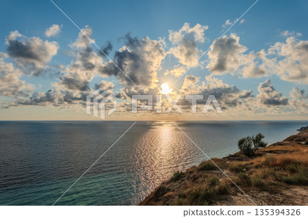 High mountain slopes to the Black Sea coast in Anapa, Russia. Coastline in sunset, beautiful sea scenery. Anapa coast landscape, high cliff 135394326