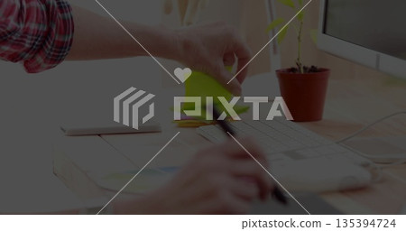 Reaching hand in plaid shirt placing sticky notes on office desk, with drawing tablet and stylus Reaching hand in plaid shirt placing sticky notes on office desk, with drawing tablet and stylus 135394724