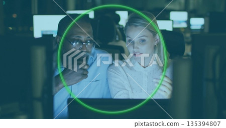 Discussing data and gesturing, two professionals working at dimly lit office desk, glowing monitors Discussing data and gesturing, two professionals working at dimly lit office desk, glowing monitors 135394807