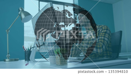 Talking man gripping smartphone while facing computer monitor at white desk, digital globe overlay Talking man gripping smartphone while facing computer monitor at white desk, digital globe overlay 135394810