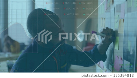 Arranging team lead placing sticky notes on wall board in open office, with laptop, copy space 135394818