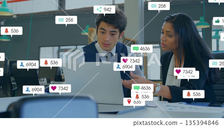 Reviewing laptop documents, professionals focusing under green lights, with social icons overlay 135394846