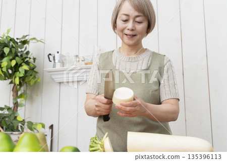Senior woman happily cooking in the kitchen Senior woman happily cooking in the kitchen 135396113