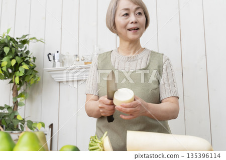 Senior woman happily cooking in the kitchen Senior woman happily cooking in the kitchen 135396114