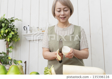 Senior woman happily cooking in the kitchen Senior woman happily cooking in the kitchen 135396116