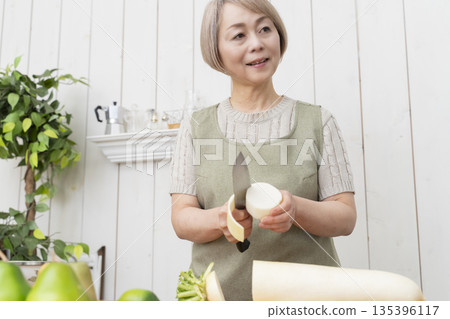 老婦人在廚房裡開心地做飯 老婦人在廚房裡開心地做飯 135396117