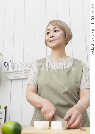 Senior woman happily cooking in the kitchen Senior woman happily cooking in the kitchen 135396130