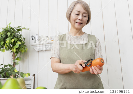 老婦人在廚房裡開心地做飯 老婦人在廚房裡開心地做飯 135396131