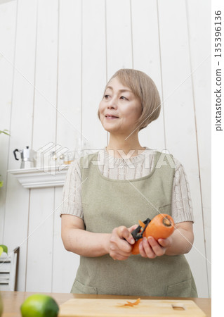 Senior woman happily cooking in the kitchen Senior woman happily cooking in the kitchen 135396136