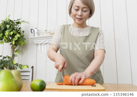 Senior woman happily cooking in the kitchen Senior woman happily cooking in the kitchen 135396146