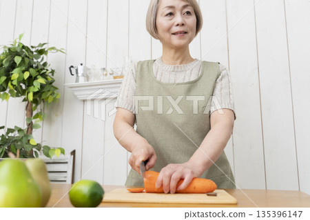 老婦人在廚房裡開心地做飯 老婦人在廚房裡開心地做飯 135396147