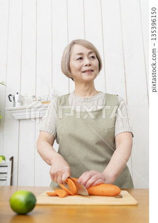 老婦人在廚房裡開心地做飯 老婦人在廚房裡開心地做飯 135396150