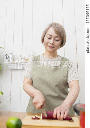 Senior woman happily cooking in the kitchen Senior woman happily cooking in the kitchen 135396155