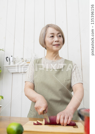 Senior woman happily cooking in the kitchen 135396156