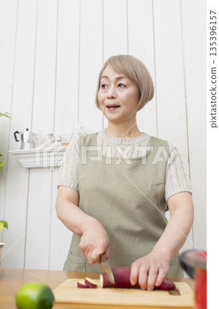 老婦人在廚房裡開心地做飯 老婦人在廚房裡開心地做飯 135396157