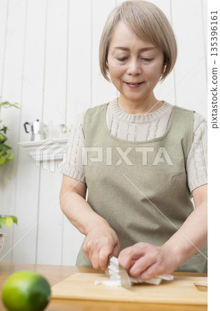 Senior woman happily cooking in the kitchen Senior woman happily cooking in the kitchen 135396161