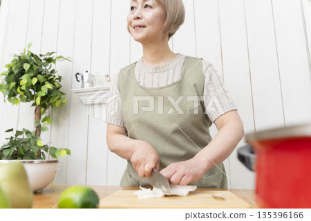 Senior woman happily cooking in the kitchen Senior woman happily cooking in the kitchen 135396166