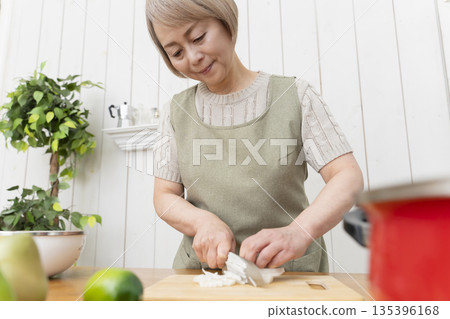 老婦人在廚房裡開心地做飯 老婦人在廚房裡開心地做飯 135396168