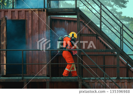 firefighter in an orange suit is walking down a metal staircase 135396988