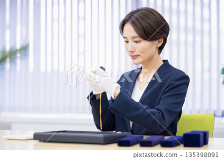 一位女士在採購公司的櫃檯評估一件商品 135398091