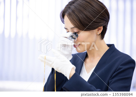A woman assessing an item at a purchasing company's counter A woman assessing an item at a purchasing company's counter 135398094