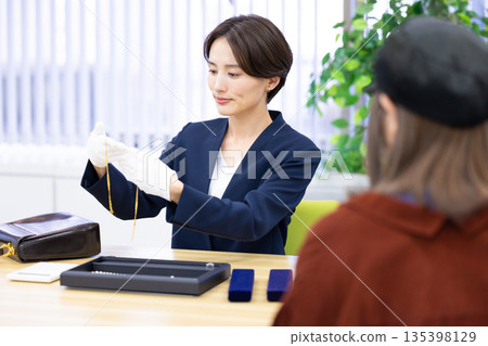 A woman assessing an item at a purchasing company's counter A woman assessing an item at a purchasing company's counter 135398129