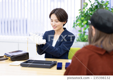 A woman assessing an item at a purchasing company's counter 135398132