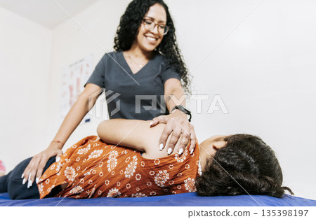 Physiotherapist rehabilitating shoulder to patient lying on her side. Shoulder and back treatment and rehabilitation concept, Woman doing shoulder rehabilitation physiotherapy 135398197
