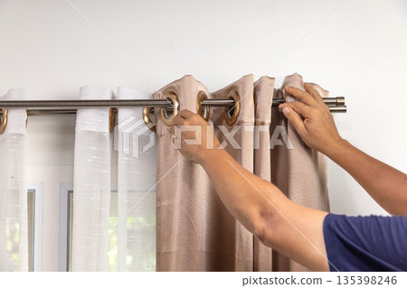 Handyman repairman hanging and fixing the curtain rod on the window 135398246