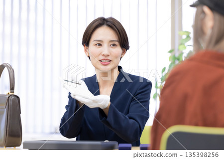 A woman assessing an item at a purchasing company's counter A woman assessing an item at a purchasing company's counter 135398256