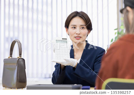 一位女士在採購公司的櫃檯評估一件商品 135398257