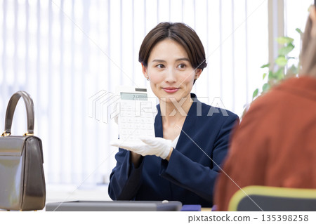 一位女士在採購公司的櫃檯評估一件商品 135398258