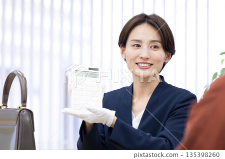 A woman assessing an item at a purchasing company's counter 135398260