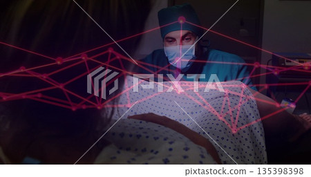 Examining doctor leaning over patient in patterned gown on hospital bed, with red digital overlay Examining doctor leaning over patient in patterned gown on hospital bed, with red digital overlay 135398398