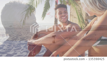 Chatting couple in swimwear sitting on tropical beach, with palm tree, white sand and ocean horizon Chatting couple in swimwear sitting on tropical beach, with palm tree, white sand and ocean horizon 135398425