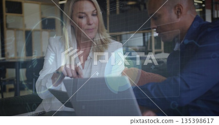 Pointing professionals in corporate attire viewing laptop in office lounge with digital overlays 135398617