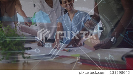 Leaning women pointing, discussing design sketches in office meeting, with digital overlay 135398643