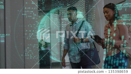 Walking coworkers wearing suits carrying tablet and bag through corridor with floating code sphere 135398659